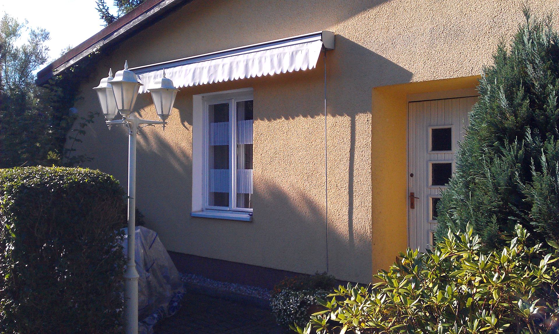Eigener Eingang mit ausgefahrener Markise über der Terrasse